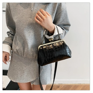 Detail of vintage black crocodile pattern bag with metal frame closure and chain strap