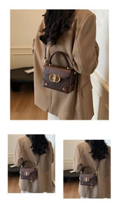 Close-up of vintage brown box bag featuring woven leather texture and gold metal buckle