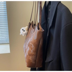 Detail of brown tote bag featuring marble texture print and a cute plush charm