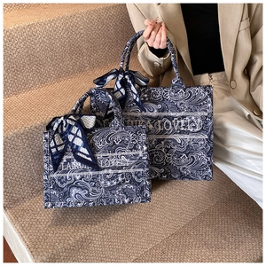 Dettaglio della borsa tote jacquard paisley blu con nastro e manico in foulard di seta
