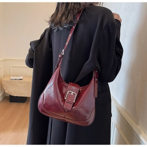 Detail view of a vintage burgundy patent leather hobo bag with a metallic buckle detail