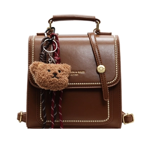 Vintage brown leather handbag and backpack with plush bear charm and golden hardware