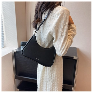 Close-up of a black matte leather hobo bag with white lettering on a model