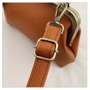 Gros plan sur cuir marron grainé avec boucle de réglage en métal bronze de style rétro