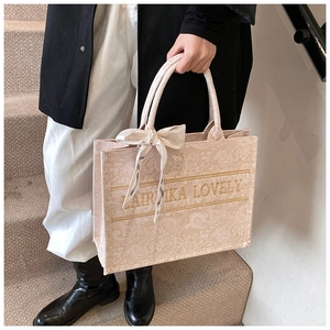 Dettaglio della borsa tote rosa paisley con tracolla logata e fiocco in seta sul manico