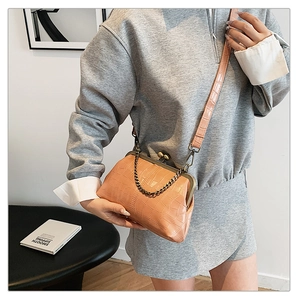 Detail view of beige crocodile embossed bag with vintage kiss lock and metal chain strap