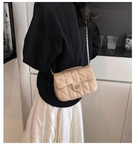 Gros plan du sac bandoulière beige matelassé avec fermoir métal et bandoulière chaîne