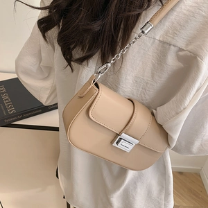 Minimalist beige leather shoulder bag with silver clasp and metal chain on a model