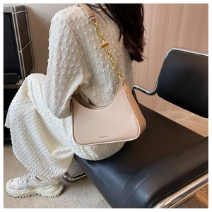 Detail of beige hobo bag with thick gold chain strap and smooth matte leather finish
