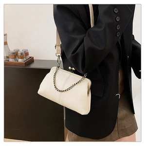 Detailed side view of cream crocodile-embossed frame bag with gold-tone chain strap