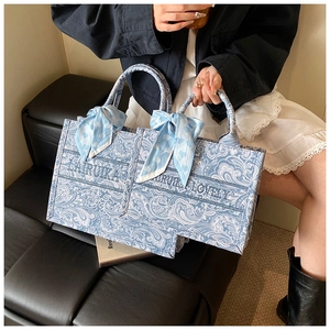 Dettaglio della borsa tote in tela paisley azzurra con ricamo e foulard di seta a cuori