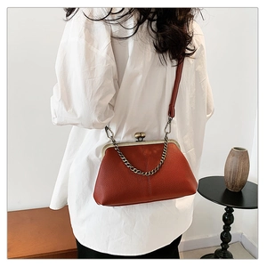 Détail du sac vintage rouge brique avec texture lychee et chaîne en laiton sur mannequin