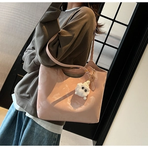 Detail of light pink glossy tote bag with gold lettering and plush monster charm