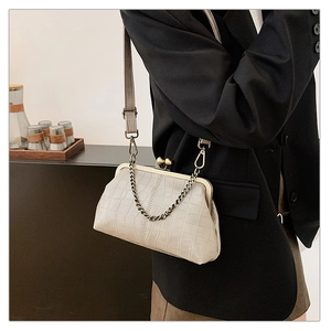 Detail of cream crocodile embossed handbag with vintage bronze clasp and chain strap