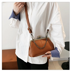 Vue détaillée du cuir grainé marron et du fermoir rétro en métal sur le sac à main
