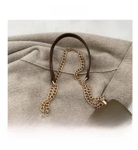 Detailed close-up of dark khaki leather handbag featuring dual metal chain straps and stitching