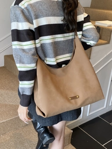 Brown large capacity suede hobo bag with gold hardware shown on shoulder in studio