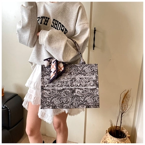 Dettaglio della borsa tote in tela con stampa paisley, foulard in seta e strisce