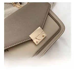 Close-up of golden rectangular metal lock on a vintage patchwork crossbody chain bag