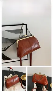 Detail of a brown croc-effect kiss-lock handbag featuring vintage bronze metal hardware