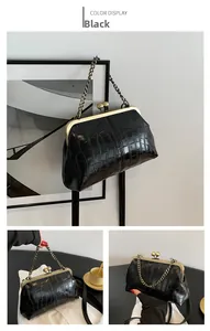 Detail of black crocodile texture bag with vintage gold metal frame and chain strap