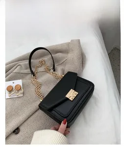 Close-up of black litchi grain leather crossbody bag with golden chain strap and metal lock