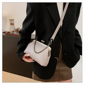 Sac à main lavande pâle avec fermoir métallique vintage et chaîne porté par un modèle