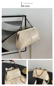 Close-up of beige crocodile pattern handbag with vintage metal kiss lock and bronze chain