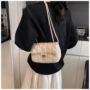 Détail d'un sac à bandoulière matelassé beige avec chaîne en métal et fermoir