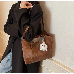 Detail of brown marble-textured tote bag with a white plush monster keychain charm