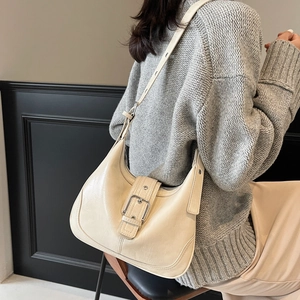 Retro cream half-moon hobo bag with metal buckle shown on a model in a cozy knit sweater