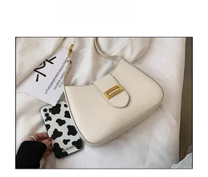 Detailed top view of cream-white leather hobo bag with gold buckle and cow print phone case