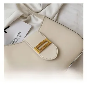 Close-up of golden rectangular metal buckle on minimalist cream white underarm bag