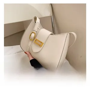 Close-up of cream baguette shoulder bag with gold oval buckle and fine chain details