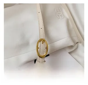 Detail of adjustable cream leather strap with gold oval buckle on fashion baguette bag