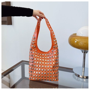Détail d'un sac à bandoulière orange vif orné de rivets argentés sur toute la surface