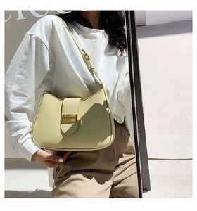 Detail of a creamy yellow leather underarm bag with a textured gold metallic buckle