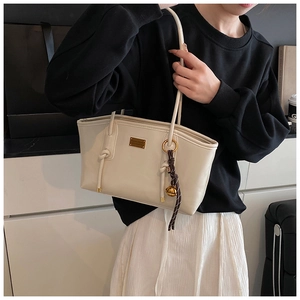 Detail of cream white leather shoulder bag with metallic logo and bell pendant charm