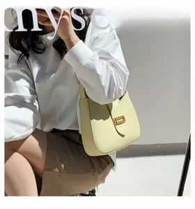 Close-up of cream half-moon baguette bag with elegant gold buckle and smooth leather