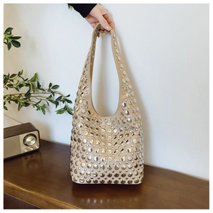 Détail d'un sac fourre-tout beige avec rivets en métal argenté et bandoulière large