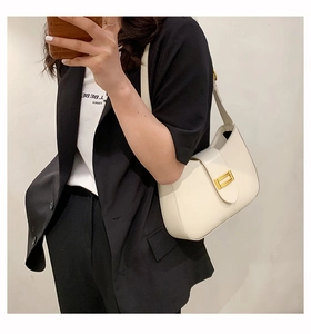 Detail view of cream-colored baguette bag with rectangular golden buckle decoration