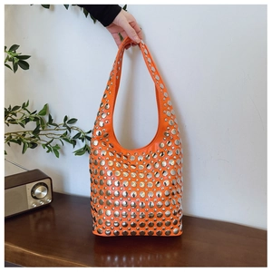 Détail du sac hobo orange orné de rivets argentés sur un simili cuir texturé mat