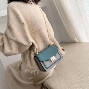 Vintage crossbody chain bag with green flap and grey body worn by model in home setting