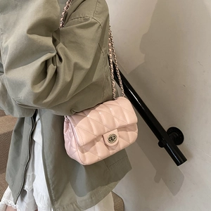 Sac à bandoulière matelassé rose avec chaîne en métal et fermoir rotatif sur un modèle