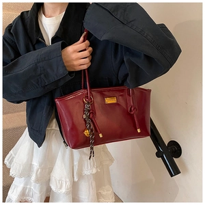 Detail of burgundy vintage shoulder bag with golden hardware and decorative charms