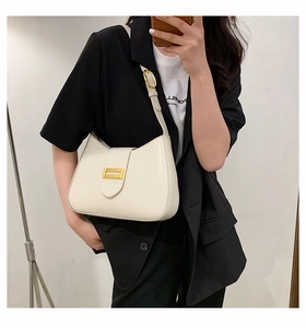 Detail of white baguette bag featuring a matte finish and gold rectangular buckle