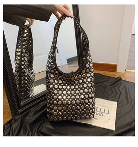 Détails des rivets argentés dégradés sur un sac seau en cuir noir avec reflet de miroir