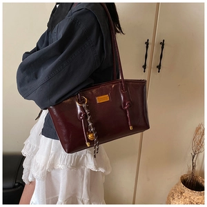 Chic burgundy underarm bag for women with gold emblem and woven pendant charm detail