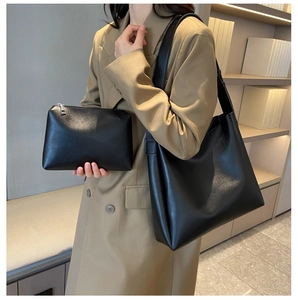 Detail of minimalist black leather tote bag and inner pouch worn with a khaki trench coat