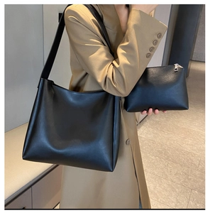 Detail view of black tote bag set with wide shoulder strap and matching clutch bag